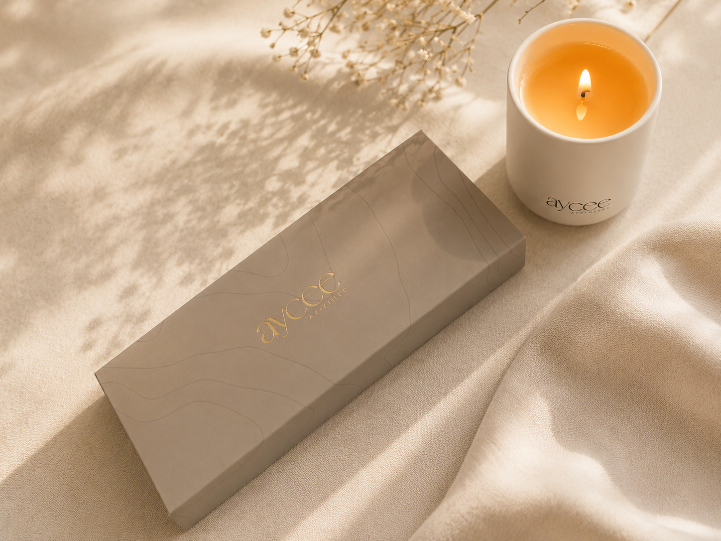 Candle care gift box from Aycee Apothec next to a lit candle in dappled sun