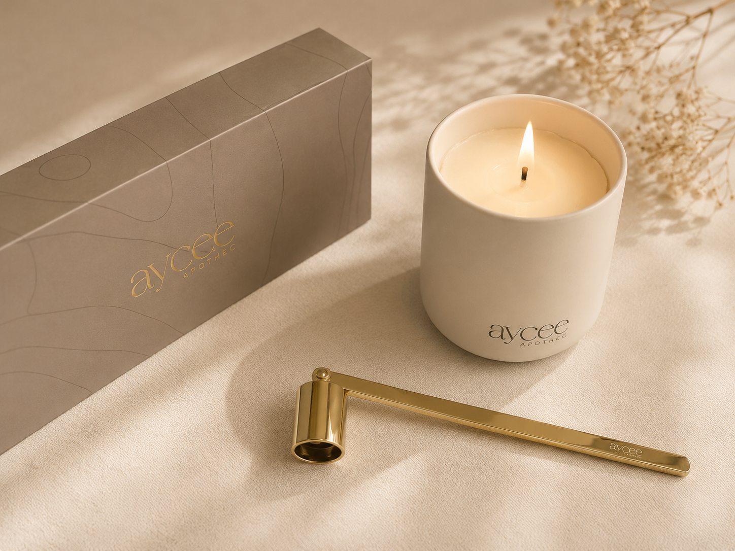 Gold wick snuffer next to lit Aycee Apothec candle in warm dappled sun and shade