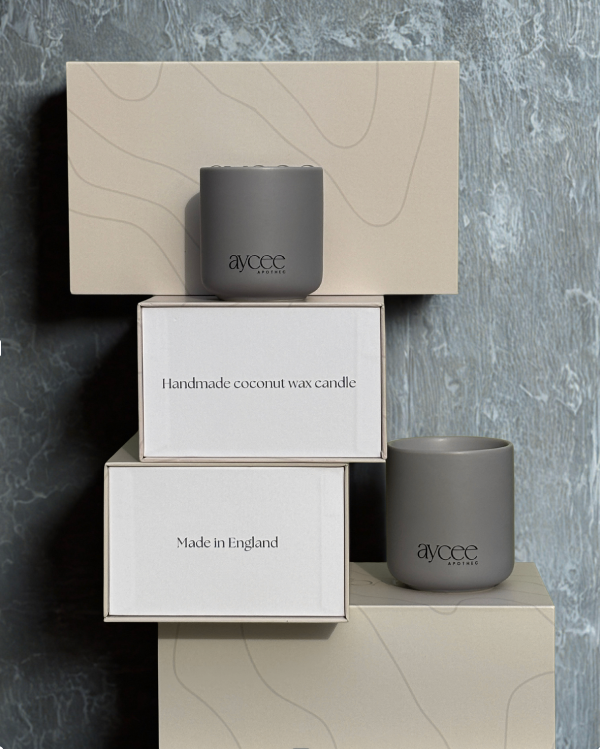 Aycee Apothec grey ceramic candle jars with packaging against a concrete surface