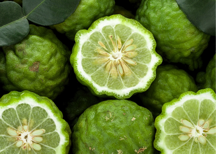 Green bergamot fruits with a few cut open to reveal their interior.