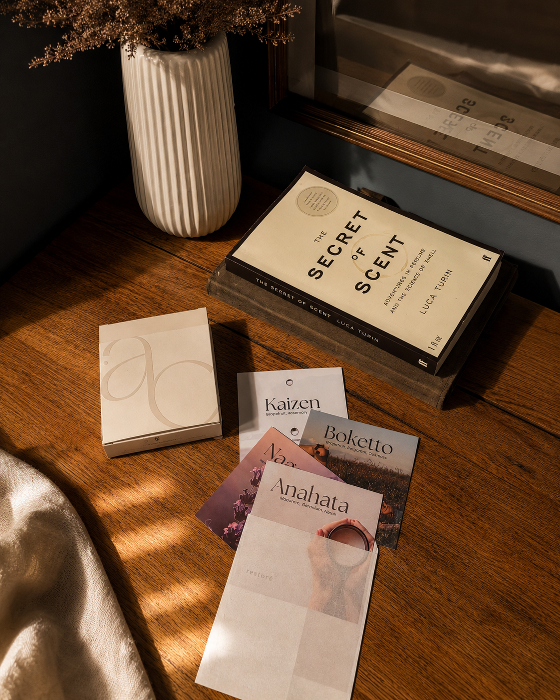 Books and stationery items on a wooden surface with a vase in the background