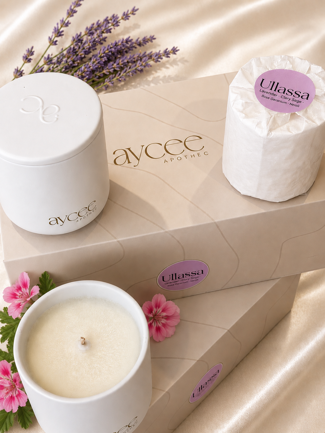 Candles and a product labeled 'Ullassa' on a beige surface with lavender and pink flowers.