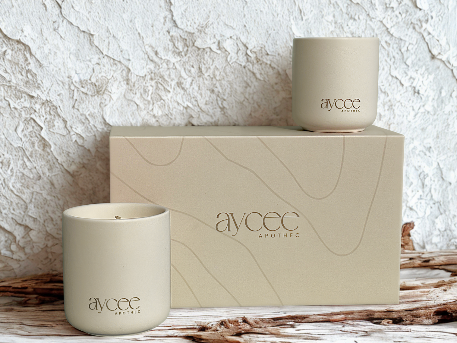 Two Aycee Apothec candles on a textured surface with a matching box in the background.